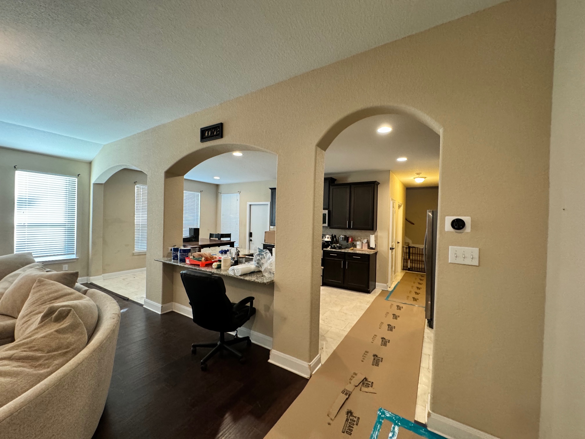 Open-plan living area with arched openings, prepped and taped for paint