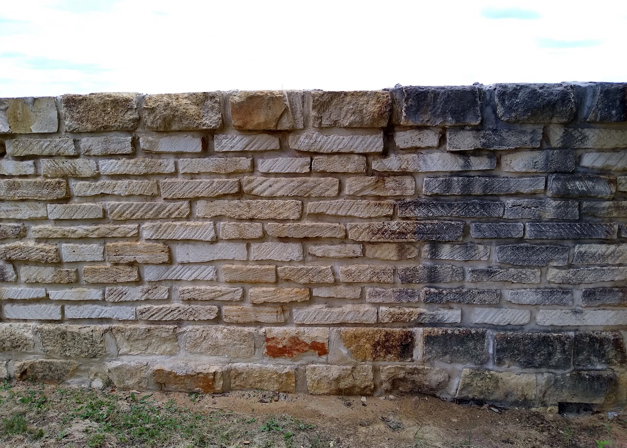 Stone wall showing mildew and grime cleaned off half the surface